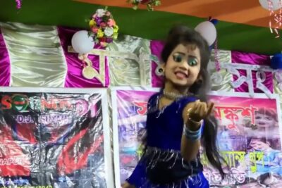 Young stage dancer in a blue costume performing on a colorful decorated stage with balloons and banners, digital teknik