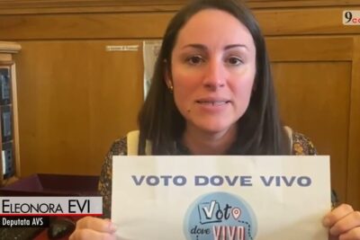 A woman holding a printed sign promoting diritto voto and local voting access