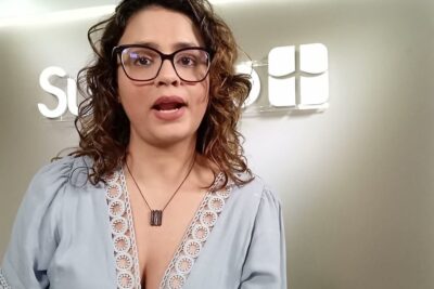 Woman with glasses speaking directly to camera in an office setting — discriminacao positiva 2