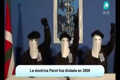 Three masked figures at a podium raising fists referencing doctrina parot 4