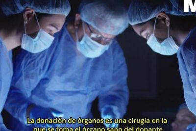 Three masked surgeons in blue scrubs and caps focused over a patient under surgical lights performing an organ donation procedure donacion organos 4