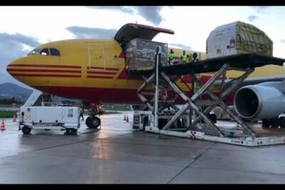 Cargo aircraft being loaded with palletized dosi vaccino and medical containers on the airport ramp
