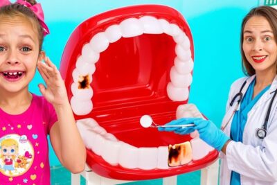 Young girl and dentist with a large red mouth model showing dark tooth decay spots e importante 1
