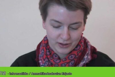 Close-up of a person wearing a patterned red scarf looking down, edistaa kestävää.
