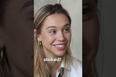 Close-up smiling young woman with blonde hair, gold hoop earrings and the word 'stoked!' referencing eksistensen zombier.