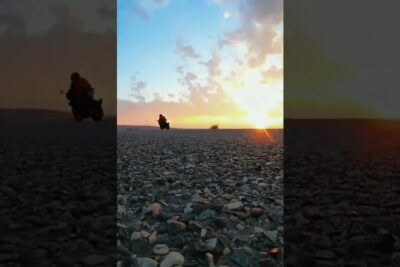 A silhouetted off-road motorbike rider crosses rocky terrain at sunset, ekstremsport vare