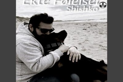 Person hugging a large black dog on a beach showing ekte folelser.