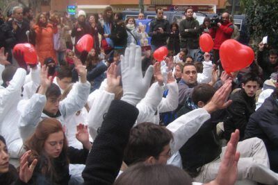 People seated and raising hands at a street demonstration with red heart-shaped balloons — el aborto 4