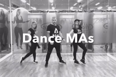 Three dancers in black athletic wear posing in a mirrored studio with large 'Dance MAs' lettering and el bicicleta 1.