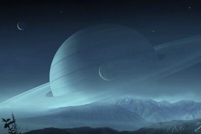 A ringed gas giant with moons looms over misty mountains in el universo 1.