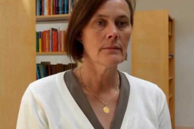 A middle-aged woman stands in a library setting in a portrait related to elever sarskilda.