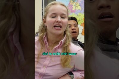 Two students in a classroom mid-discussion with a visible map in the background highlighting elevernes laring