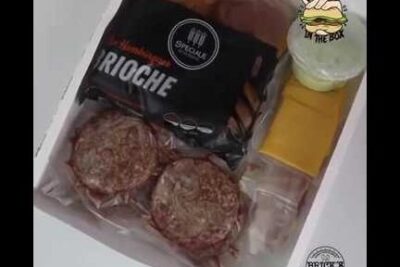 Boxed burger kit with packaged brioche buns, two burger patties, cheese slices and a condiment jar in embalagem brik 1