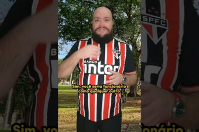 Bearded man in red, white and black striped soccer jersey standing in a park, emprego juvenil 1