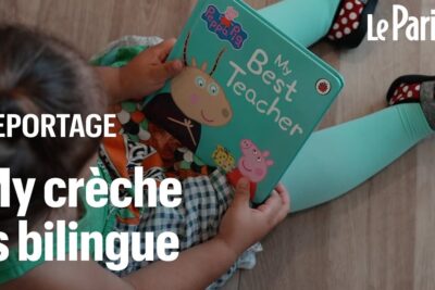 Child seated on a wooden floor holding a colorful Peppa Pig board book, representing enfants bilingues learning