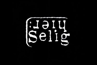Inverted white grunge 'selig' typographic logo on solid black background es wichtig 12