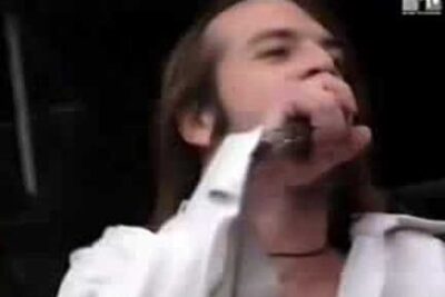 Male singer holding a microphone on stage mid-performance with a visible music network logo es wichtig 47
