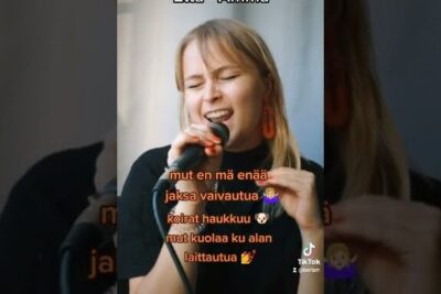 Female singer passionately performing into a microphone in a vertical video titled etta elama 3.