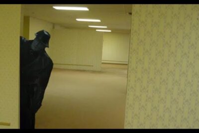 Dim yellow office corridor with patterned wallpaper and a cloaked figure peeking, labeled existenz backrooms 1