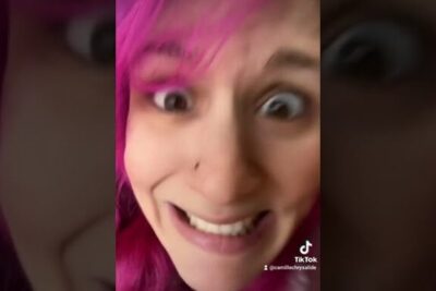 Close-up of a surprised pink-haired person with a nose piercing, faire tatouer 1
