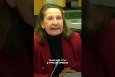 Elderly woman at a microphone in a meeting advocating favor vegetarianismo