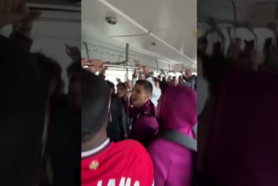 Commuters singing and holding overhead bars on a crowded bus to feire julen.