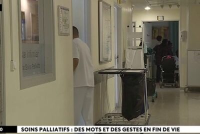 Hospital corridor with a healthcare worker, gurney and wheelchair in a palliative care area fin vie 9.