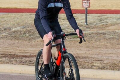 Cyclist in helmet and sunglasses riding a black-and-red road bike for att 44 on a paved path