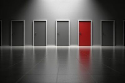 Row of closed doors with one red door highlighting choices and dilemmas about fordeler och nackdelar med mansklig kloning.