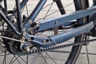 Close-up of a bicycle rear belt drive, hub assembly and disc brake showing belt teeth and frame tension points with fordele ulemper 4