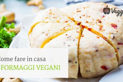 Sliced creamy formaggi vegani wheel with herbs, red pepper flakes and cashews on a white plate