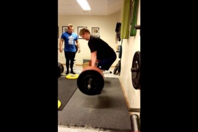 Athlete performing a heavy barbell deadlift under coach supervision forstaelse verden 1.