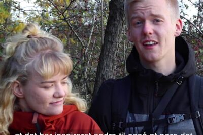 Two young hikers standing by berry-covered shrubs in autumn discussing forurening ogsa