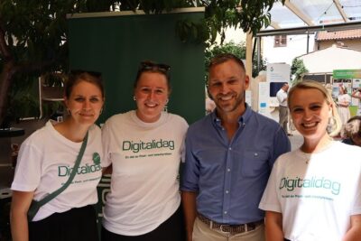 Four smiling event staff at a Digitalidag booth advocating framja inkludering at an outdoor community fair.