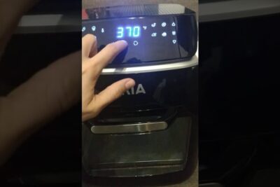 Hand touching the touchscreen of a freidora aria showing 370°F