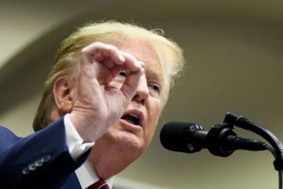 Man speaking into a microphone with a pointed hand gesture emphasizing freie meinungsausserung.