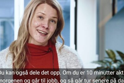 Smiling woman with microphone in an office setting promoting fysisk utdanning and short activity breaks.