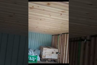 Neatly stacked lumber and wooden ceiling panels stored indoors for genbruge materialer.