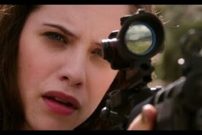 Young woman aiming through a rifle scope, representing generacion z focus.