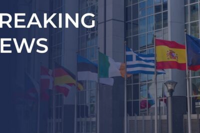 Modern glass building with a row of international flags and a bold 'BREAKING NEWS' banner, giornata continua 1.