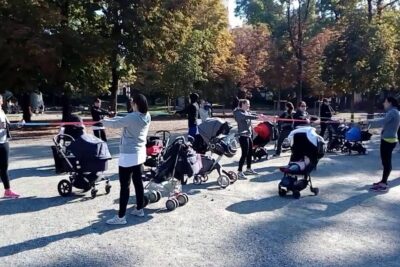 Group of young mothers exercising with strollers and resistance bands in a park, giovani mamme 1