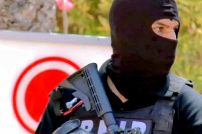 Masked Tactical Officer on Patrol — give 16 arige Security Response, armed officer in a balaclava and tactical vest holding a rifle and scanning the area.