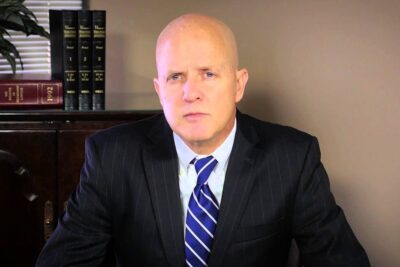 Male attorney in pinstripe suit and blue tie seated at a desk with law books, representing habeas corpus 12.