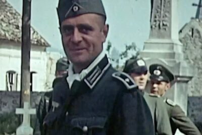 Close-up of a uniformed soldier in front of gravestones and a monument, henkilokohtaiset vaikutelmat 1.