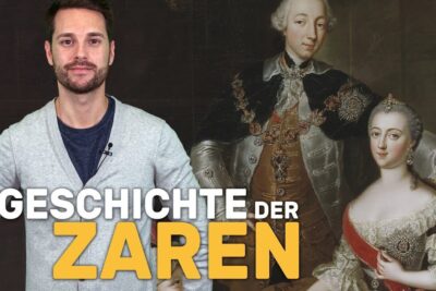 A male presenter stands beside an ornate painted tsar and tsarina portrait with bold yellow 'ZAREN' text, herrschaft zaren 1