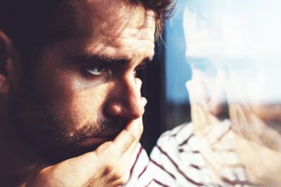 Close-up of a pensive man staring out a window with his reflection visible, hevder jorden.