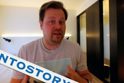 A man gesturing in a modern hotel room, huonot puolet.