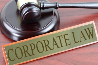 Polished wooden gavel and sound block beside a 'CORPORATE LAW' nameplate on a wooden desk il diritto 1.