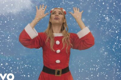 Woman in red Santa costume reaching up as snow falls il natale 1