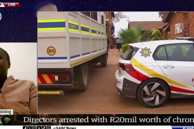 Television report showing law enforcement vehicles and a truck at a property during illegal mining coverage.